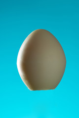 white chocolate egg on a blue background, close up, copy space