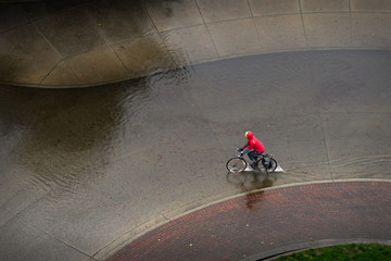 Bicycling in the Rain. A downpour floods a Vancouver street as a bicyclist rides through.