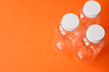 Three ecoplastic bottles on colour background , environmental concept, space for text