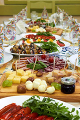 Beautiful served table for wedding or other celebration in restaurant with dishes of cheese, sausage, vegetables (eggplant, tomatoes, bell pepper)