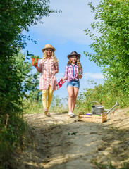 Girls with gardening tools. Sisters helping at farm. On way to family farm. Kids siblings having fun at farm. Eco farming concept. Agriculture concept. Adorable girls in hats going planting plants