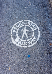 A pedestrial walkway symbol is painted on an asphalt road.