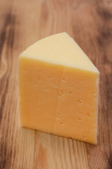 Cut piece of cheese close-up on a wooden background