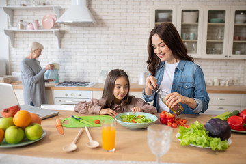 Obraz na płótnie Canvas Mom with daughter preparing fresh vegetable salad.