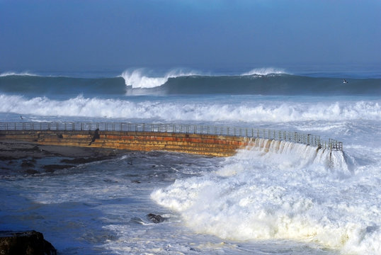 Huge waves from a large winter swell sweep over the walkway at the Children's Pool in La Jolla, CA.
