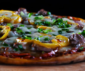 Italy hot pizza with yellow pepper, green onions and pieces of bасon isolated on black background