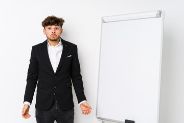 Young business coaching arabian man shrugs shoulders and open eyes confused.