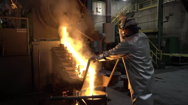 The gold melting process. Two people in protective clothing working.