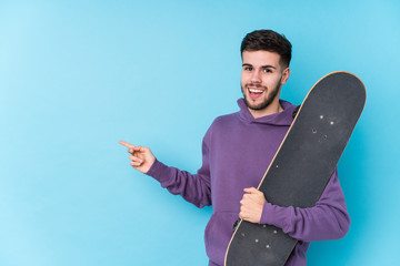 Young caucasian skater man isolated smiling and pointing aside, showing something at blank space.