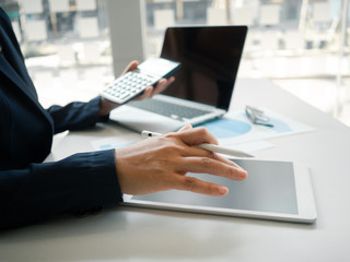 Business woman hand working at a computer, using calculator and laptop to calculate an account. Finance and accounting concept.
