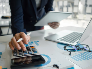 Business woman hand working at a computer, using calculator and laptop to calculate an account....