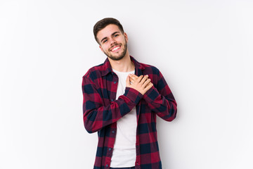 Young caucasian man posing in a white background isolated has friendly expression, pressing palm to chest. Love concept.