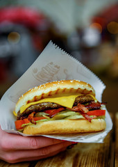 Woman hand is holding a fresh burger before eating on street
