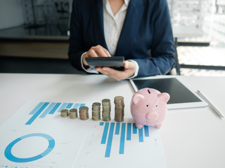 piggybank and business women working and calculate expenses with calculator and laptop. stak of...