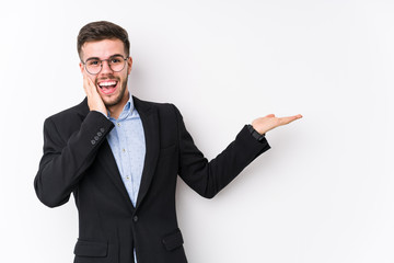 Young caucasian business man posing in a white background isolated Young caucasian business man holds copy space on a palm, keep hand over cheek. Amazed and delighted.