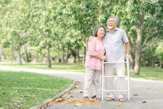 Asian senior couple talking a walk with walker in the park