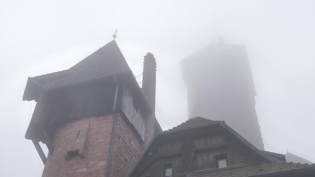 Torre y tejados medievales de fortaleza del terror con niebla y viento