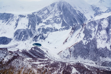 Snow-capped mountain peaks and deep gorges in the area of cross pass, Georgia.  Round lake in the gorge