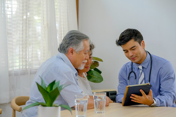 The doctor explain about old woman health with old man support beside in the living room of their house.