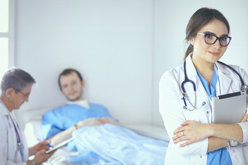 Fototapeta premium Doctor checking heart beat of patient in bed with stethoscope