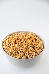 Bowl of whole grain oat cereal on a white background, back view. Heart shapes cereal. 