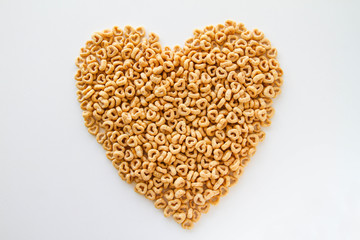 Whole grain oat cereal in a heart shape on a white background, top view. Heart shapes cereal. 
