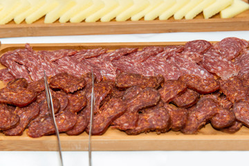 Catering food for the event - different types delicacies of meat and cheese arranged in wooden plate over white background - selective focus