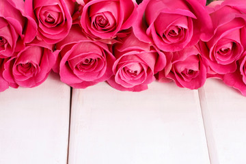 Pink roses on white wooden background, copy space.