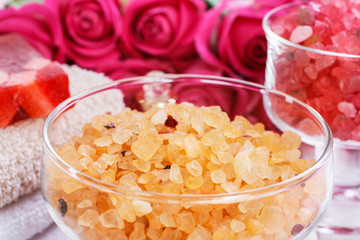 Glass bowl with yellow sea salt. Pink roses in the background.