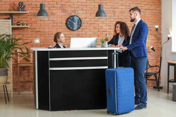 Young female receptionist working with guests in hotel