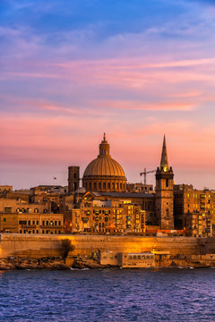 Malta, Valletta, City skyline at sunset, boats in Marsamxett Harbor in foreground