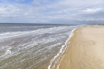 Beautiful seaside landscape - view of the beach near the embankment of The Hague with people making promenade, the Netherlands