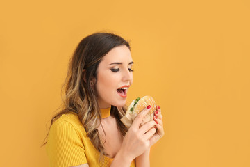 Portrait of beautiful young woman with burger on color background