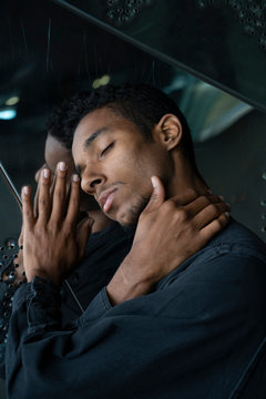 Portrait of young man with closed eyes at mirrored wall