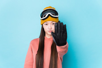 Young chinese woman wearing ski clothes isolated standing with outstretched hand showing stop sign, preventing you.