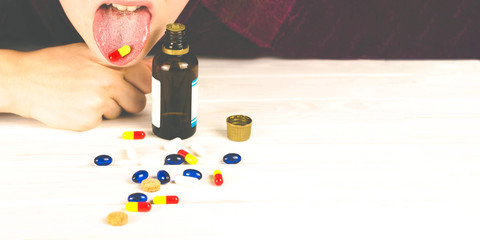 Cropped image of a disgruntled young lady holding a bright pill in her mouth on her tongue. Medicine and health care concept.Treatment and prevention of various diseases and viruses.