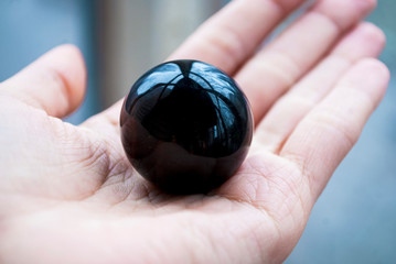 Ball of natural black obsidian in hand