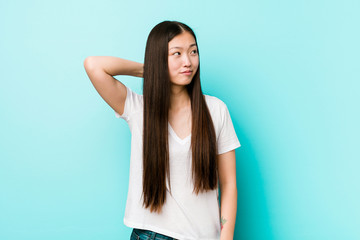 Young pretty chinese woman touching back of head, thinking and making a choice.