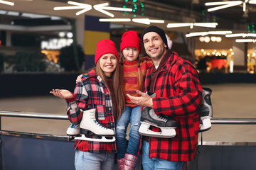 Obraz na płótnie Canvas Happy family with ice skates near rink