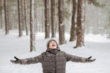 Portrait of boy catching snowflakes in winter forest