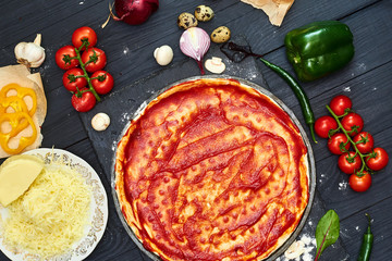 Cooking pizza. Pizza dough topped with tomato sauce and ingredients.