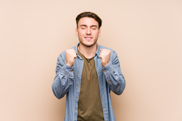 Young caucasian man posing isolated raising fist, feeling happy and successful. Victory concept.