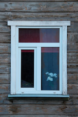 plastic window in a wooden frame in a rustic house with color on the windowsill