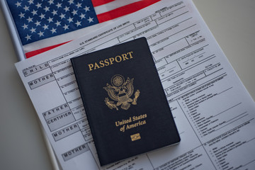 U.S. standard certificate of live birth application form next to flag and passport of USA. Birthright citizenship concept.