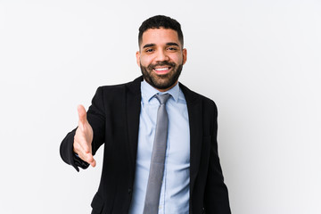 Young latin business woman against a white background isolated stretching hand at camera in greeting gesture.
