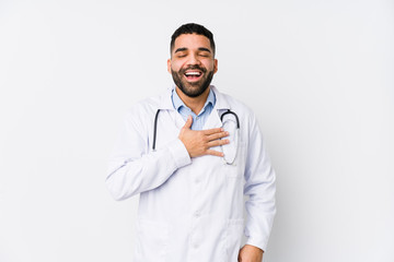 Young arabian doctor man isolated laughs out loudly keeping hand on chest.