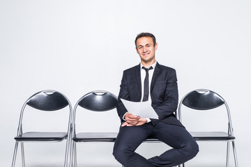 Ready for interview. Thoughtful man in formalwear holding paper while sitting at the chair in...