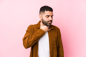 Young latin man against a pink background isolated suffers pain in throat due a virus or infection.