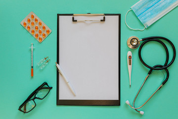 Doctor's desk top view. Stethoscope, pills, glasses and notebook on a colored background.