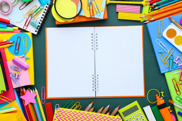 Different school supplies with blank sheet of paper on green chalkboard